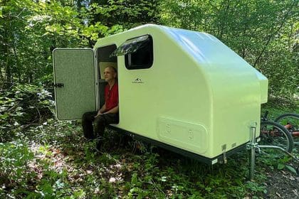 Caravan da bici compatta alpencamper eco slide out agganciata a una bicicletta