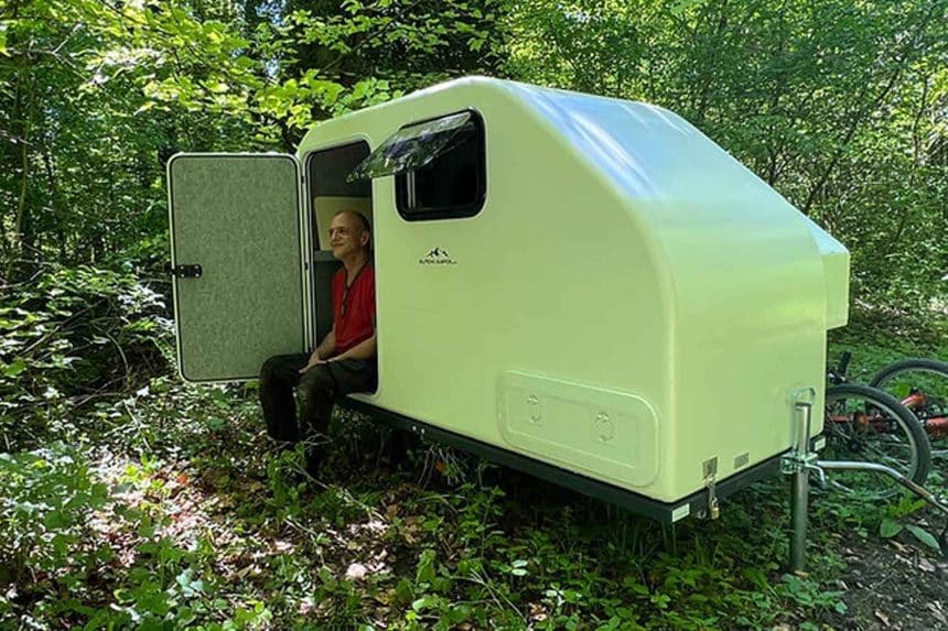Caravan da bici compatta alpencamper eco slide out agganciata a una bicicletta